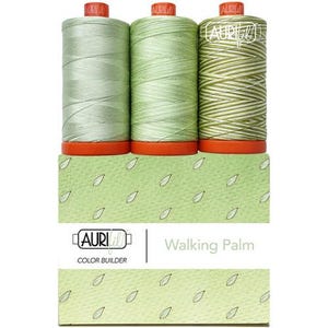May include: Three spools of Aurifil thread in varying shades of green, featuring orange bases and the Aurifil logo. The packaging is light green with a leaf pattern and the text "AURIfil COLOR BUILDER" and "Walking Palm" printed on the front.