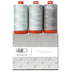 May include: Three spools of Aurifil thread in shades of green and gray, atop a box with the text "Frangipani." The spools have orange bases and red tops. The box has a leaf pattern and the Aurifil logo.