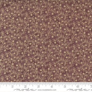 May include: A fabric with a repeating pattern of tan star and vine designs on a dark burgundy background. The fabric is marked with a ruler along the bottom edge, with measurements in inches.