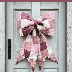May include: A large quilted bow made of patchwork fabric in various shades of pink, mauve, and white with floral patterns. The text reads: THE BIG GIANT QUILTED BOW, Designed to be reversible, Scrappy and fat quarter friendly, 3 style options included, A beginner-friendly sewing pattern + video tutorial by: LGC LINDSEY GRACE CREATES.