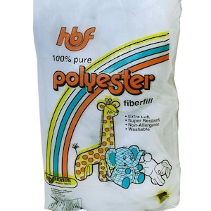May include: A white bag of polyester fiberfill with the text "100% pure polyester fiberfill." The bag features a rainbow design and illustrations of a giraffe, elephant, and bunny. Additional text includes "Extra Loft, Super Resilient, Non-Allergenic, Washable."