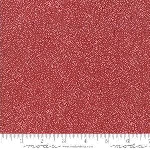 May include: Red fabric with a speckled pattern of small, off-white dots. The fabric has a ruler along the bottom edge, with the word "moda" and the website address "www.modafabrics.com" printed on it.