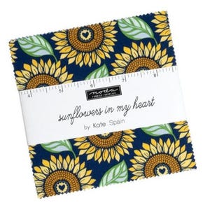 May include: A stack of fabric squares with a sunflower pattern. The fabric features yellow sunflowers with brown centers and green leaves on a navy blue background. The text "sunflowers in my heart" is printed on a white band.