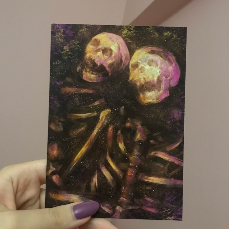 Puede incluir: Dos cr&aacute;neos humanos con tonos amarillos y rosados brillantes est&aacute;n rodeados por una pila de huesos. Los cr&aacute;neos est&aacute;n posicionados uno cerca del otro, con un cr&aacute;neo ligeramente m&aacute;s alto que el otro. El fondo es una superficie oscura y texturizada con toques de morado y verde.