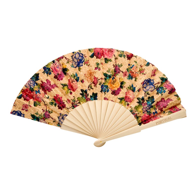 May include: A hand fan with a floral print on a cork background. The fan is made of wood and has a wooden handle. The fan is closed and the handle is facing the viewer. The fan has the word "PORTUGAL" printed on the handle.