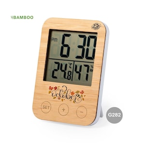 Puede incluir: Un reloj digital de madera con una pantalla en blanco y negro que muestra la hora como 6:30 PM y la fecha como 24/47. El reloj tiene un fondo blanco con un diseño floral y la palabra "Octubre" impresa en él. El reloj tiene botones etiquetados "SET", "+" y "-".