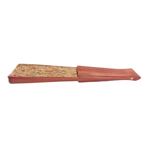 May include: A closed, brown, wooden hand fan with a floral pattern on the front. The fan is closed and the handle is visible.