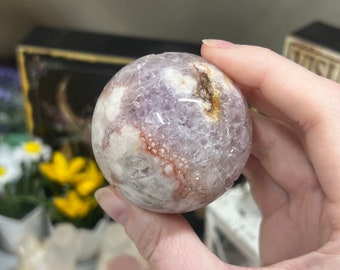 May include: A purple and white agate sphere with a swirling pattern. The sphere is smooth and polished.
