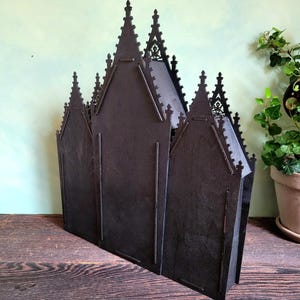 K&ouml;nnte beinhalten: Ein dunkelbraunes, lasergeschnittenes Holzmodell einer Kathedrale. Das Modell verf&uuml;gt &uuml;ber mehrere T&uuml;rme und gew&ouml;lbte Fenster mit einem detaillierten, gotischen Design. Die Struktur ist freistehend und scheint aus geschichtetem Holz zu bestehen.