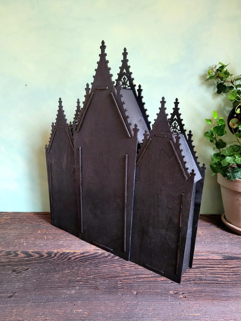 K&ouml;nnte beinhalten: Ein dunkelbraunes, lasergeschnittenes Holzmodell einer Kathedrale. Das Modell verf&uuml;gt &uuml;ber mehrere T&uuml;rme und gew&ouml;lbte Fenster mit einem detaillierten, gotischen Design. Die Struktur ist freistehend und scheint aus geschichtetem Holz zu bestehen.