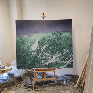 May include: A large canvas painting on an easel in a studio setting. The painting depicts a landscape with green and white brushstrokes, suggesting a mountainous or wave-like scene.