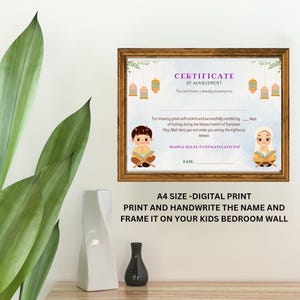 May include: A printable certificate of achievement for Ramadan. The certificate features a light blue background with a pink border. The text "CERTIFICATE OF ACHIEVEMENT" is in a purple font. The certificate is decorated with illustrations of two children, a boy and a girl, both wearing traditional Islamic clothing and holding books. The certificate is framed in a brown frame.