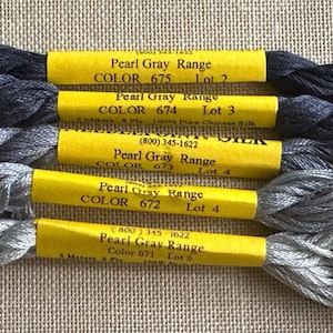 May include: Five skeins of embroidery floss in shades of gray, from dark charcoal to light silver. Each skein has a yellow label with the text "Pearl Gray Range" and color numbers.