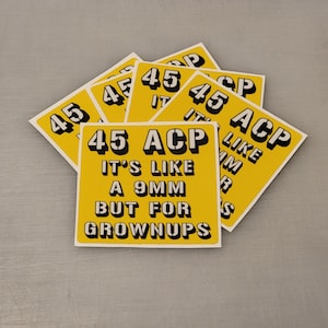 Puede incluir: Un montón de pegatinas amarillas con el texto "45 ACP Es como una 9 mm pero para adultos" impreso en negro.