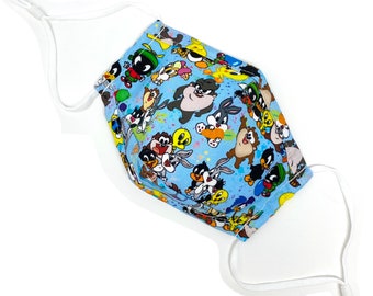 May include: A blue face mask with a colorful cartoon print featuring characters from Looney Tunes. The mask has white elastic ear loops.