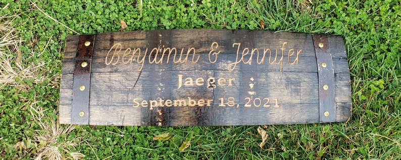 May include: A dark brown wooden sign with metal accents and the text "Benjamin & Jennifer Jaeger September 18, 2021" engraved in gold.