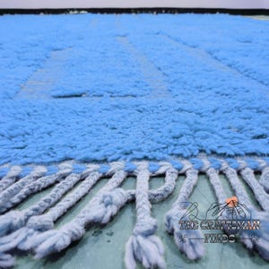 May include: A light blue shag rug with a fringe border. The rug is made of soft, fluffy fibers and has a subtle texture.