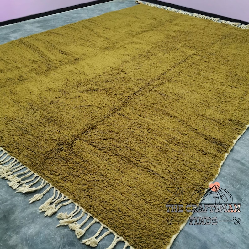 May include: A large, plush, olive green rug with a fringe border. The rug is made of a soft, fuzzy material and has a subtle texture.