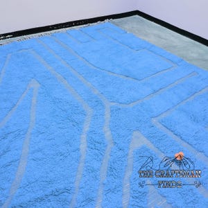 May include: A light blue shag rug with a white geometric pattern. The rug has a fringe border.