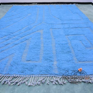 May include: A blue and white geometric patterned rug with fringe. The rug has a modern design and is made of a soft, plush material.
