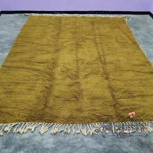 May include: A large, mustard yellow rug with a subtle pattern and fringe edging. The rug is made of a soft, plush material.