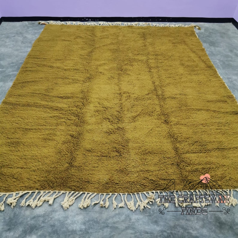 May include: A large, mustard yellow rug with a subtle pattern and fringe edging. The rug is made of a soft, plush material.
