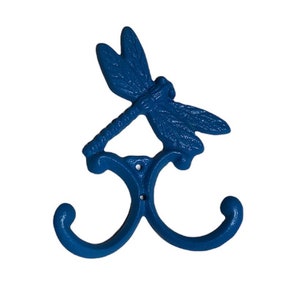 May include: Blue cast iron dragonfly wall hook with two hooks. The dragonfly is in a flying position with its wings spread out.