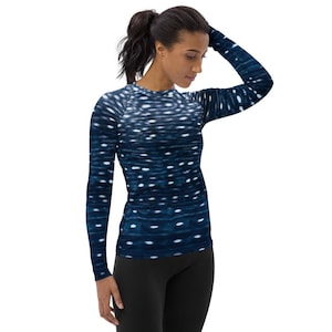 Puede incluir: Una camiseta de manga larga con un patrón azul y blanco que se asemeja a un tiburón ballena. La camiseta está hecha de una tela elástica y cómoda, perfecta para superponer o usar sola.