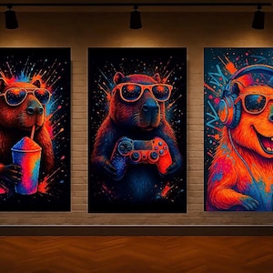 May include: Set of three vibrant art prints featuring capybaras with sunglasses. One drinks a colorful beverage, another holds a game controller, and the third wears headphones. The artwork uses neon colors against a black background.