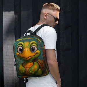 May include: A backpack featuring a cartoon turtle design. The turtle has a green head and shell, with a yellow beak and large purple eyes. The background is teal with orange and green accents. The backpack has black straps and a zipper.