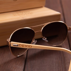 Puede incluir: Gafas de sol aviador marrones con montura dorada y patillas de bamb&uacute;. Las gafas tienen lentes de degradado marr&oacute;n y las palabras "DEVID" est&aacute;n grabadas en la patilla derecha.