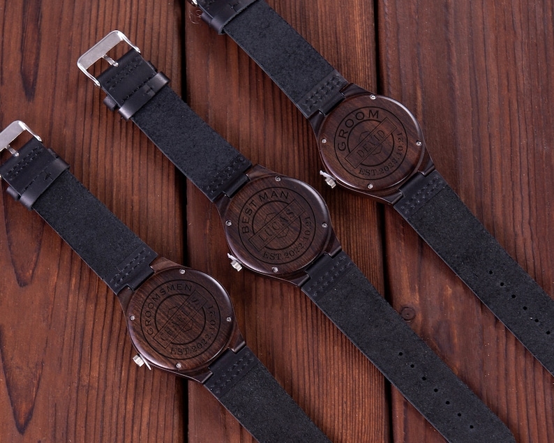 Pu&ograve; includere: Tre orologi da polso in legno con cinturini in pelle nera. Gli orologi hanno diverse incisioni sul quadrante, tra cui "Groom", "Best Man" e "Groomsmen".