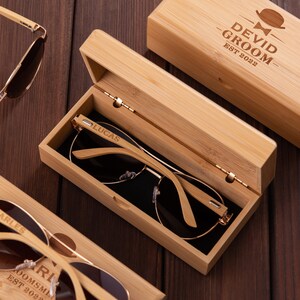Puede incluir: Tres cajas de madera con gafas de sol dentro. Las cajas est&aacute;n grabadas con los nombres "Lucas", "Charles" y "Devid Groom Est 2022".
