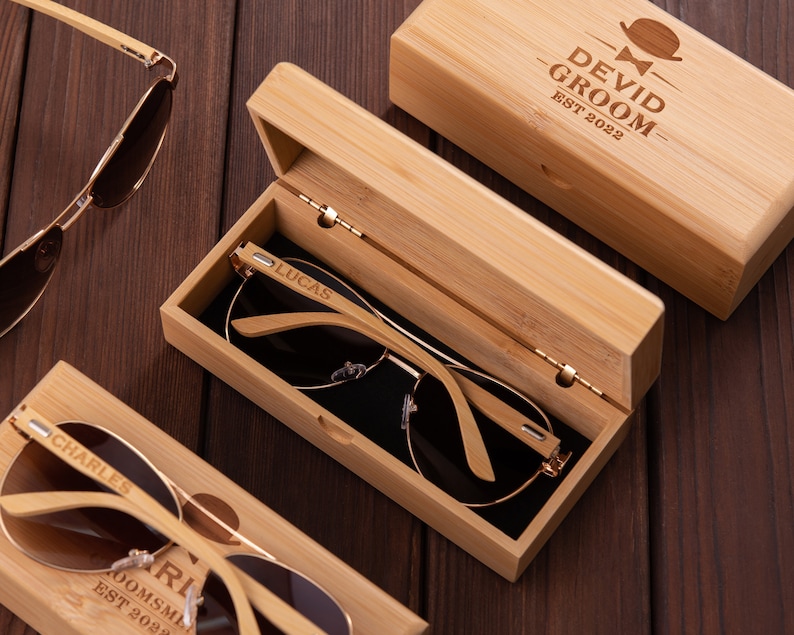 Puede incluir: Tres cajas de madera con gafas de sol dentro. Las cajas est&aacute;n grabadas con los nombres "Lucas", "Charles" y "Devid Groom Est 2022".