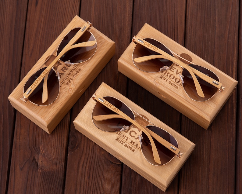 Puede incluir: Cuatro cajas de madera con gafas de sol en su interior. Cada caja tiene un nombre y un t&iacute;tulo diferentes grabados en la parte delantera. Los nombres son Charles, Lucas, Devid, y el t&iacute;tulo es "Best Man", "Groomsme" o "Ev Roo".
