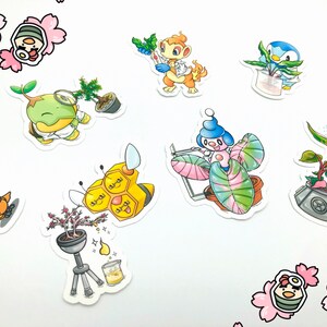 May include: A set of nine colorful stickers featuring cartoon characters with plants. The characters are a bee, a monkey, a bird, a pink creature, a green creature, and a pink creature with a flower. The stickers are on a white background with pink flower stickers.