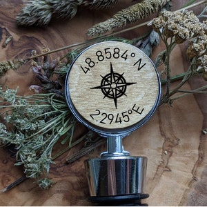May include: Wooden bottle stopper with a compass design and the coordinates 48.8584° N 2.2945° E. The stopper is made by Little Woodpecker Studio.