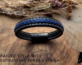 May include: Black leather bracelet with a blue braided band and white stitching. The bracelet has a magnetic clasp.