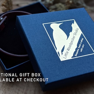 May include: A blue gift box with a white woodpecker logo and the text "Little Woodpecker Studio" and "Bespoke, hand-crafted with care".