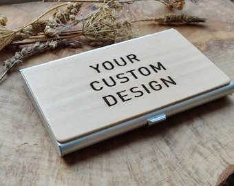 May include: A wooden card holder with a silver metal frame. The wood has the text "YOUR CUSTOM DESIGN" engraved on it.