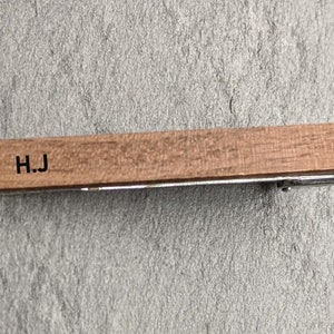 May include: A wooden tie bar with the initials "H.J." engraved on it.