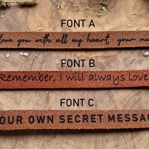May include: Three leather bracelets with different fonts. The top bracelet reads "I love you with all my heart, your munchkin". The middle bracelet reads "Remember, I will always love you". The bottom bracelet reads "YOUR OWN SECRET MESSAGE".