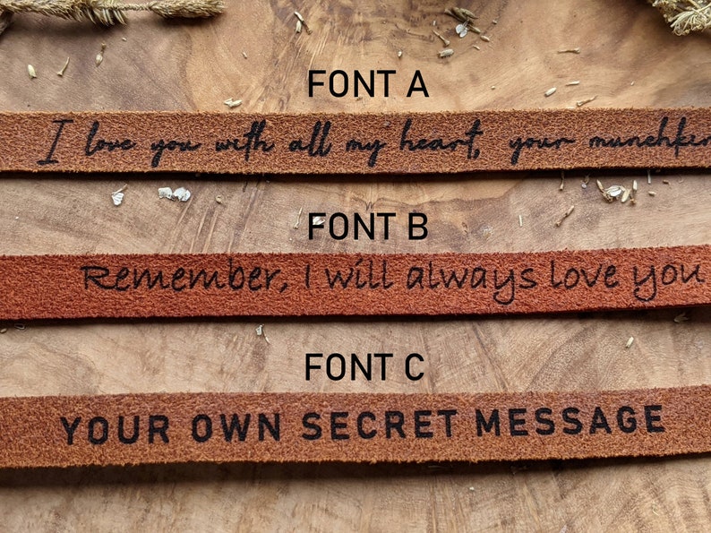 May include: Three leather bracelets with different fonts. The top bracelet reads "I love you with all my heart, your munchkin". The middle bracelet reads "Remember, I will always love you". The bottom bracelet reads "YOUR OWN SECRET MESSAGE".
