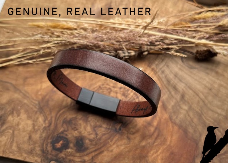 May include: A brown leather bracelet with a magnetic clasp. The bracelet is on a wooden surface with a brown background. The text "Genuine, Real Leather" is visible at the top of the image.