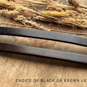 May include: Close-up of two leather straps, one black and one brown, with a textured surface. The text "CHOICE OF BLACK OR BROWN LEATHER" is at the bottom. Dried wheat stalks are in the background.
