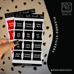 May include: Two sheets of planner stickers featuring month tabs from January to December. The stickers are black with white text in a gothic font. The top sheet has black tabs, while the sheet underneath features red tabs. NONY DESIGN + CO is printed.