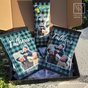 Op de afbeelding: Een geschenkdoos met drie op maat gemaakte snackverpakkingen. De verpakkingen hebben een zwart-blauw geruit patroon, de tekst "Happy Father's Day" en een familiefoto. De tekst "EST. 2018" is ook inbegrepen.