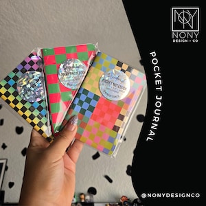 May include: Three pocket notebooks in clear plastic sleeves, each featuring a colorful checkered pattern. The labels state Handmade Pocket Notebook 3.5 x 5.5, 48 pages, 80gsm, dotted paper. The designs include purple-yellow, red-green, and multi-colored squares.