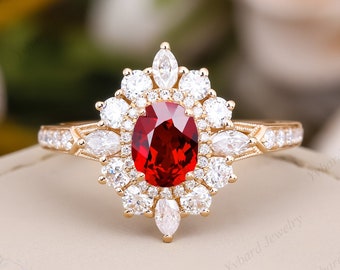 May include: A gold ring with a large red oval gemstone surrounded by smaller white gemstones. The ring has a delicate floral design.