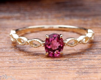 Puede incluir: Un delicado anillo de oro con una piedra ovalada rosa engastada en una banda retorcida.